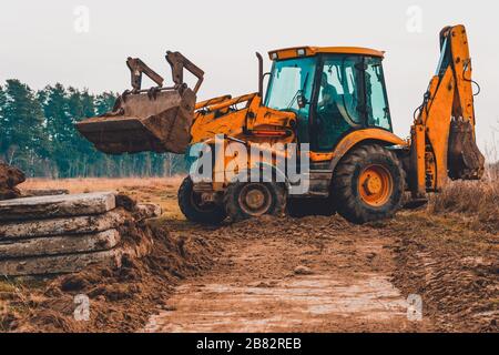 A close-up excavator loads soil into the bucket for further road installation. Stock Photo
