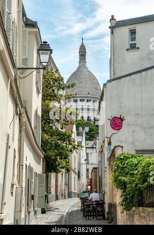 Small alley in Montmartre with view of the dome of the Basilica Sacre-Coeur, Paris, Ile-de-France, France Stock Photo