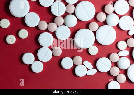 Heap of white pills, tablets, capsules on red background. Drug prescription for treatment medication health care concept wth copy space Stock Photo