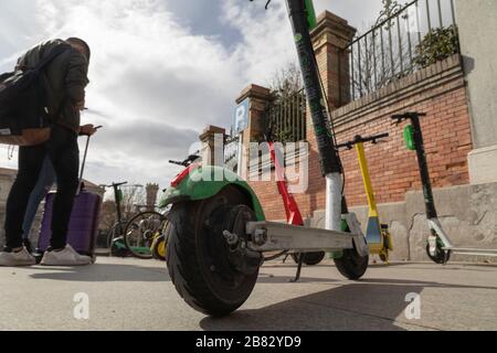 Madrid, Spain - February 25, 2020: Electric scooters, from several urban mobility service companies, left carelessly in the middle of the sidewalk. Stock Photo