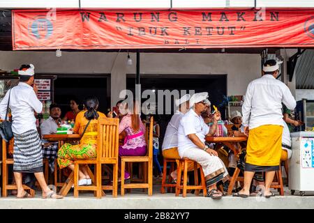 A Group Of Balinese Hindu People Sitting At A Restaurant, Besakih Temple, Bali, Indonesia. Stock Photo