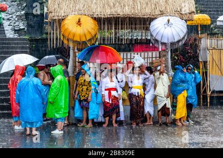 Visitors and Tourists Shelter From The Rain At The Batara Turun Kabeh Ceremony, Besakih Temple, Bali, Indonesia. Stock Photo