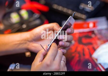 A man is repairing a mobile phone. In the frame, his hands and details of the device. repair shop for gadgets Stock Photo