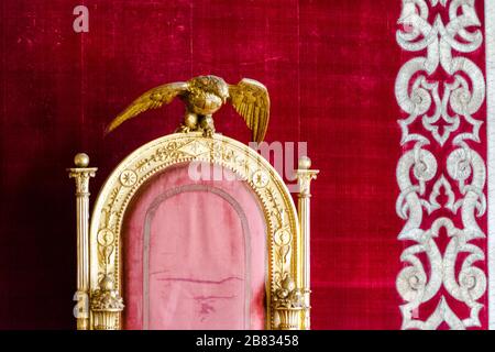 Royal Palace of Naples, Italy, september 2017. The old red and gold throne of the Borbone dynasty of two Sicilies reign with the symbol of the house, Stock Photo