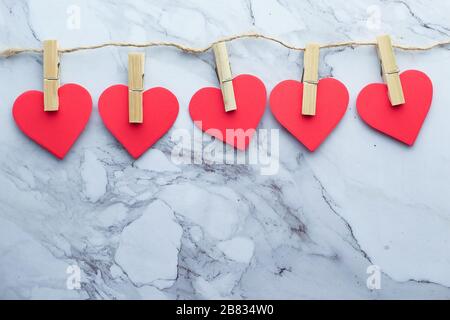 Clothes pegs and red wooden hearts on rope isolated on white background Stock Photo
