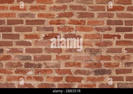 Detail of the texture, in the shade, formed by the rows of reddish bricks of one of the walls of the Conde Duque Cultural Center, in Madrid, Spain. Stock Photo