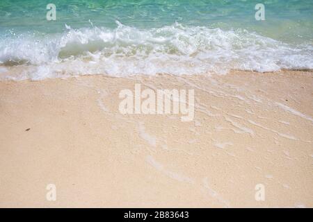 Soft blue ocean wave on clean sandy beach. The blue sea soft wave on the sand are continuously and beautifully touching the shore Stock Photo