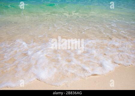 Soft blue ocean wave on clean sandy beach. The blue sea soft wave on the sand are continuously and beautifully touching the shore Stock Photo