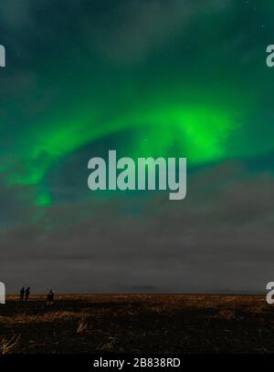 By standers looking at the developing Aurora Borealis outside of Vik, Iceland. Stock Photo