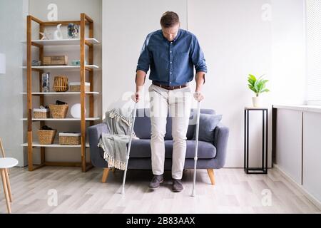 Disabled Young Man Using Crutches To Walk Stock Photo