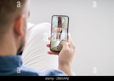 Close Up Of A Person's Hand Using Home Security System On Mobile Phone Stock Photo