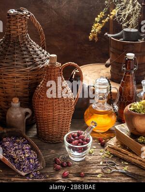 Rose hips and dried herbs with vintage bottles on a rustic background Stock Photo