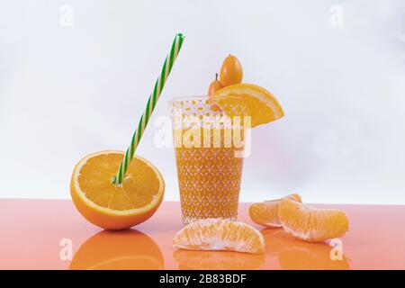 Small oranges, one half orange, sliced oranges and an orange juice on an orange table - Nutritious and tasty orange Stock Photo