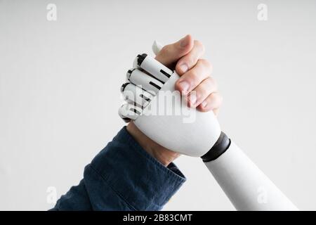 Close-up Of Businessperson Shaking Hands With Robot Stock Photo