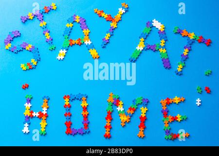 Top view to message words Stay at home made of kids from puzzle pieces. Pandemic self quarantine at home Stock Photo