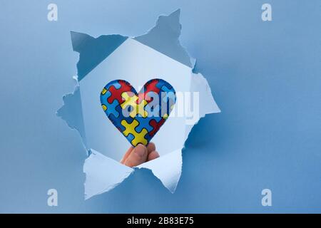 World Autism Awareness, concept with puzzle or jigsaw pattern on heart in paper cut hole Stock Photo