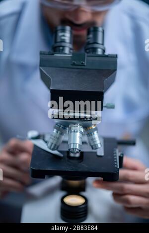Young scientist looking through a microscope in a laboratory. Young scientist doing some research. Stock Photo