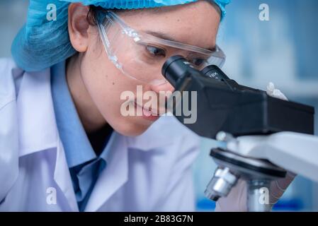 Young scientist looking through a microscope in a laboratory. Young scientist doing some research. Stock Photo