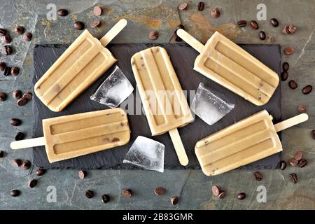 Coffee and chocolate popsicles on a slate server, overhead view over a stone background Stock Photo