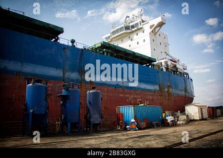 A large tanker cargo ship is being renovated and painted in shipyard dry dock Stock Photo