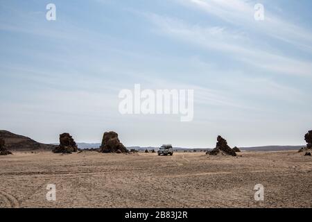 Africa, Djibouti, Lake Abbe. Landscape view of lake Abbe. An SUV is parked next to some rock formations Stock Photo