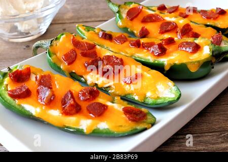 Group of jalapeno poppers with cheese and pepperoni close up on a white serving plate Stock Photo