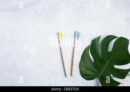 Bamboo toothbrushes and green leafs on stone table Stock Photo