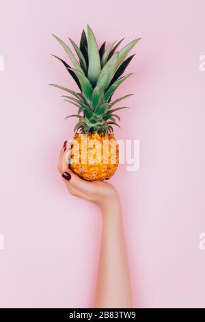 Hands with pineapple on stylish pink background. Stock Photo