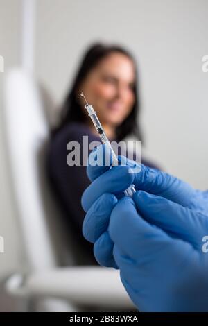 Patient getting a vaccine shot from a doctor/nurse against a virus during a virus pandemic Stock Photo