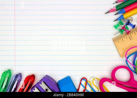 Colorful school supplies corner border over a lined paper background Stock Photo