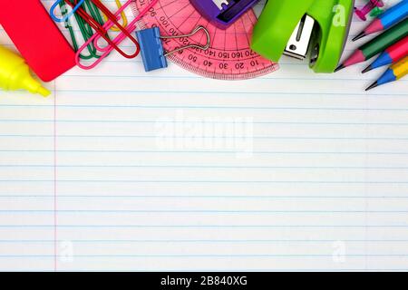 Colorful school supplies top border over a lined paper background Stock Photo