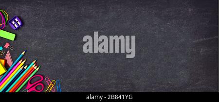 School supplies corner border banner. Top view on a chalkboard background with copy space. Back to school concept. Stock Photo