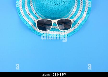 Summer hat with sunglasses. Top view, minimal concept over a blue background. Top border orientation. Stock Photo