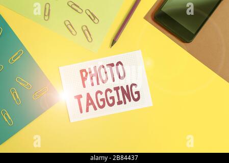 Handwriting text writing Photo Tagging. Conceptual photo identify someone on the photo that you share social media Paper sheets pencil clips smartphon Stock Photo