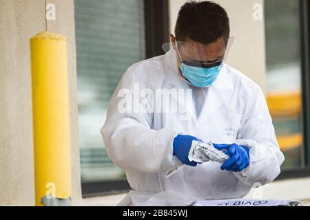 Healthcare worker prepares to administer COVID-19 test to patients in drive-thru clinic Stock Photo