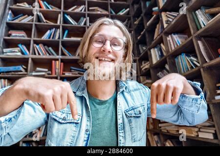 Happy male blogger influencer pointing on subscription looking at camera. Stock Photo