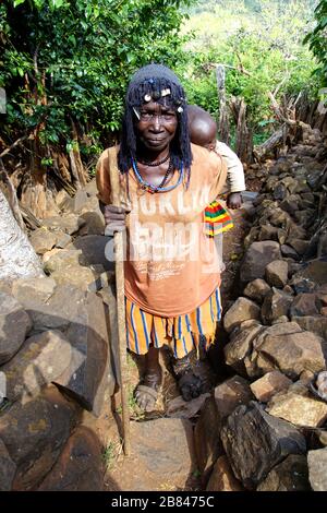 Local Konso Woman with a Baby on her Back on a Walk through Gamole Walled Village Stock Photo