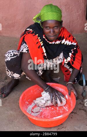 Woman mashing Dough for Injera in a Red Plastic Tub Stock Photo