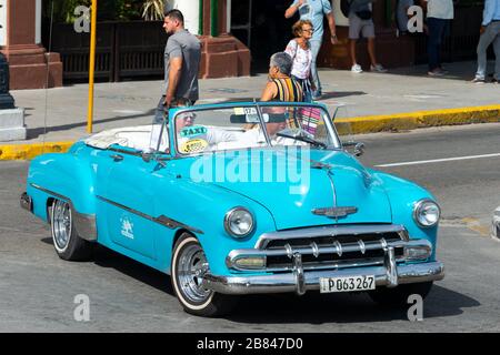 Chevrolet classic car in light blue/cyan color in Havana, Cuba downtown offering taxi and tour services. Chrome plated details vehicle in La Habana. Stock Photo
