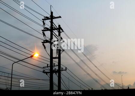 Electric pole power Tangle wire danger, wire electrical energy and light at street road on sky background evening Stock Photo