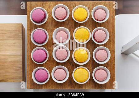 Multicoloured macaroon in cups served on wooden tray Stock Photo
