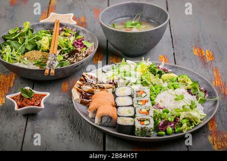 Pan-Asian dishes in bowls. Rice with spices and beef, salad with beans, rolls with salmon and avocado, fish soup. Tasty and healthy nutrition Stock Photo