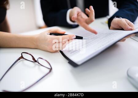 Two Businesspeople Hand Analyzing Document Over Glass Desk Stock Photo