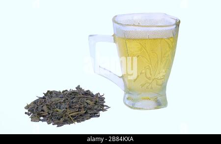 Green tea in a cup with heap of dried green tea leaves isolated on white background.Side view. Stock Photo