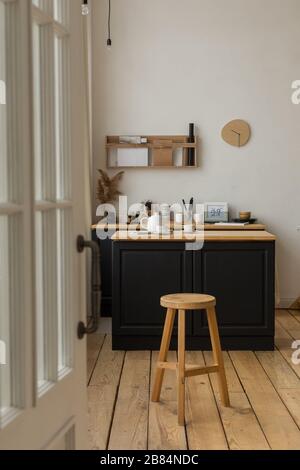 Entrance to light kitchen with served table and stool