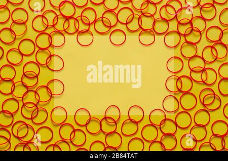 Red color elastic rubber bands put on yellow background with empty space for background and abstract concept. Stock Photo