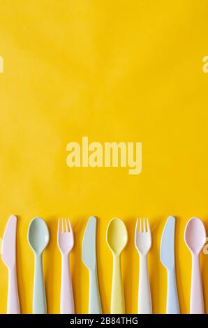 Colorful fork, spoon and knife on yellow background with empty space for text. Stock Photo