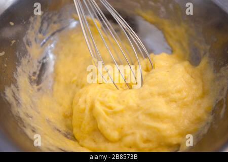 Whipping yellow cream with a whisk close up Stock Photo