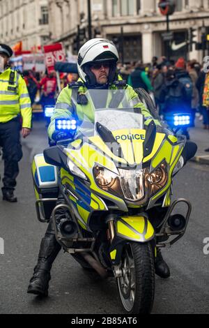 Metropolitan police motorcycle officer, ensuring road safety and crowd control, whilst on duty during the Million Women Rise demonstration. Stock Photo