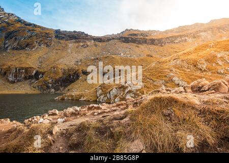 Huge lake in the mountains with a little house on the dock. Nice blue sky with some clouds. Shot in Romania, Transfagarasan Stock Photo